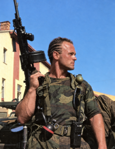 In uniform with a drum-fed machine gun and radio
